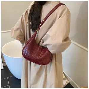 Close-up of wine red woven leather crescent bag with elegant gold metal buckles