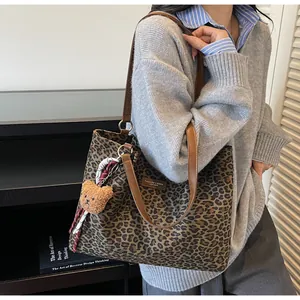 Détail du sac cabas en toile léopard avec lanières en cuir et breloque ours en peluche