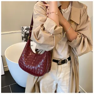 Detail of burgundy woven leather crescent hobo bag with gold hardware and shoulder strap