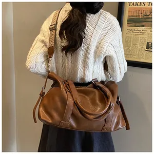 Detail of vintage brown tote bag featuring wide woven strap and soft leather texture
