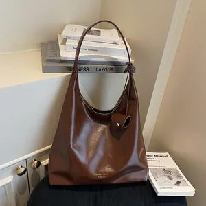 Deep brown oversized hobo shoulder bag in glossy leather with knotted strap and mini pouch