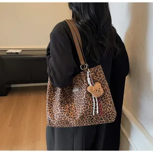Vue latérale du sac cabas en toile léopard avec lanières en cuir et charme d'ours