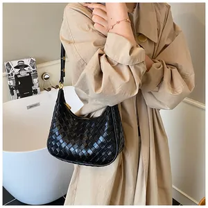 Detail shot of black woven leather hobo bag with gold hardware worn as a shoulder bag