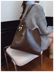 Détail d'un sac cabas en cuir ciré marron foncé avec pompon en perles de bois colorées