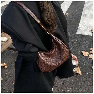 Close-up of woven leather texture and gold buckle on a brown crescent shoulder bag