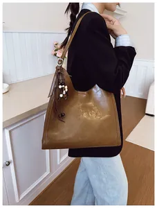 Détail d'un sac cabas marron vintage avec gland en perles de bois et logo discret