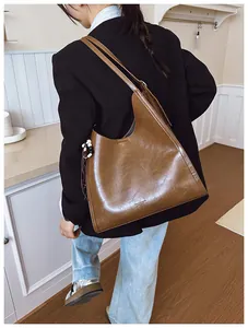 Détail d'un sac cabas en cuir marron avec pendentif en perles et texture polie