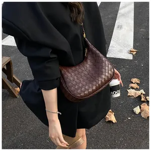 Close-up of woven dark brown crescent shoulder bag with leather texture detail