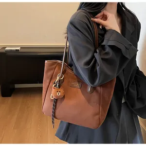 Braune Wildleder-Tote Bag mit Lederriemen und Bären-Anhänger am Model im Business-Look