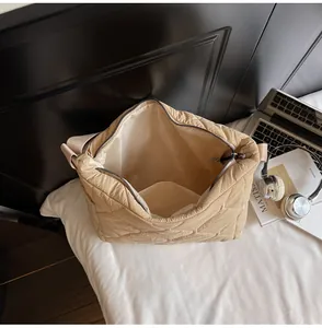 Interior view of beige quilted crossbody bag with laptop and headphones on desk