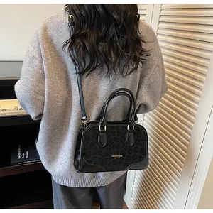 Detail of black leopard texture handbag with adjustable strap worn by model in a cozy setting
