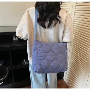 Detail of blue quilted padded crossbody bag with wide shoulder strap and soft texture
