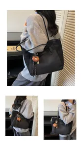 Große schwarze Nylon-Tragetasche mit Mode-Label und braunem Plüschbär-Anhänger
