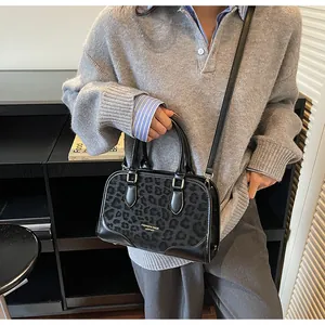 Detail of grey leopard print handbag featuring leather panels and gold logo lettering
