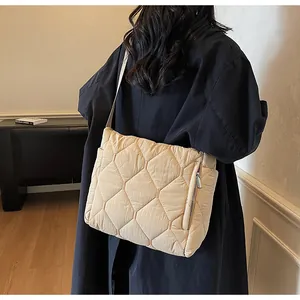 Beige quilted nylon crossbody bag with hexagonal patterns shown on female model