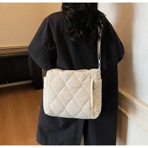 Detail of cream quilted cotton padded crossbody bag with side zipper and long strap