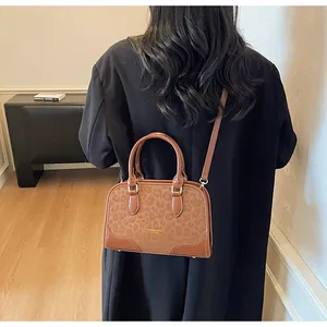 Rear view of a model wearing the brown leopard print crossbody bag with gold lettering