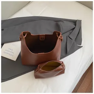 Brown faux leather tote bag and inner pouch set on white soft fabric with blazer background