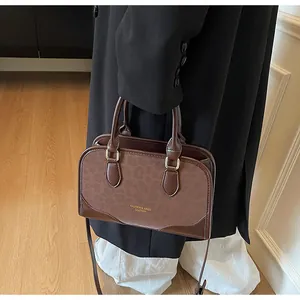 Detail of a brown leather handbag with leopard print panel and gold metallic buckle hardware