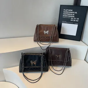 Three elegant butterfly motif tote bags in black and brown hues with metallic chain straps