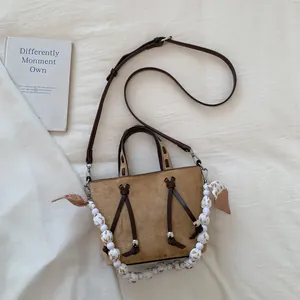 Detailed view of the khaki suede tote bag featuring artistic beads and a leather strap