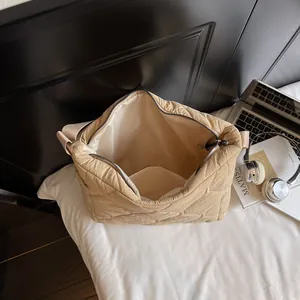 Chic beige quilted shoulder bag with interior pocket and zipper on white bedding
