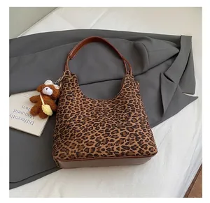 Detail van luipaardprint hobo tas met bruine leren riem en pluche beer bedeltje