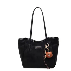 Große schwarze matte Shopper Tasche mit Bärenanhänger und Schultergurt auf Weiß