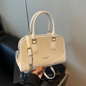 Elegant cream white Boston handbag with gold hardware and adjustable crossbody strap