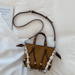 Detail shot of brown faux suede tote bag with spotted scarf and metal eyelets
