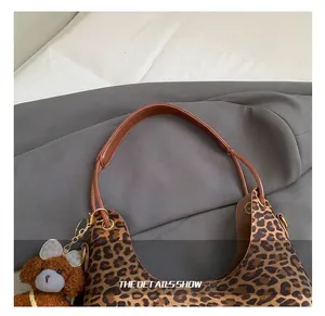 Detail van luipaardprint tote met bruine lederen riem en schattige beer hanger decoratie