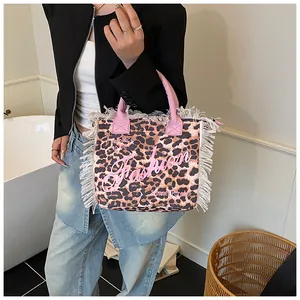 Detail of leopard print tote bag featuring white fringe edges and pink fashion lettering