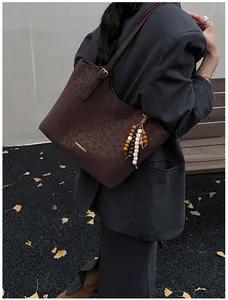 Vue détaillée du sac cabas léopard avec pendentif perlé et lettrage doré de mode