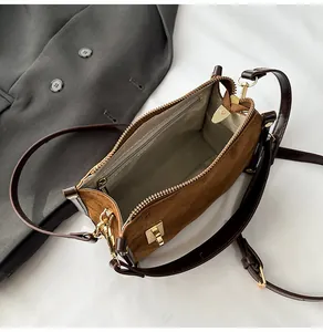 Detail view of the brown suede crossbody bag interior with a zipper pocket and beige lining