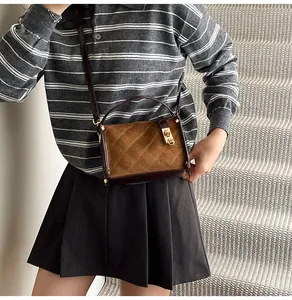 Detail of brown crossbody bag featuring quilted stitching and metal twist lock closure