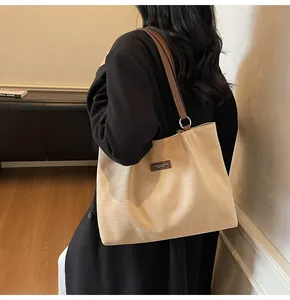 Detailansicht der aprikosenfarbenen Veloursleder-Tote Bag mit braunen Lederriemen und Logo