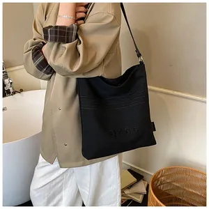 Detail of black canvas bucket bag featuring embroidered QZBG letters and long strap