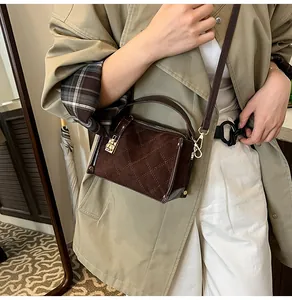 Close-up of brown quilted leather square bag with gold hardware on trench coat
