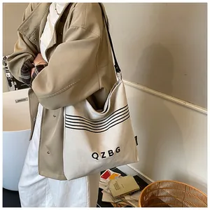 Detail of canvas bucket bag featuring letter print and stylish black shoulder strap