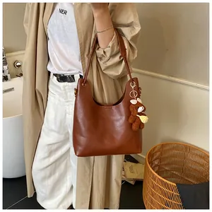 Brown tote bag on model shoulder with cute bear pendant in cozy indoor setting
