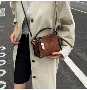 Detail view of brown quilted suede crossbody bag with gold rotating lock and black straps