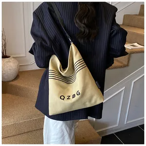 Detail shot of beige canvas bucket bag with black QZBG lettering and striped pattern