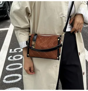 Detail of brown suede crossbody bag with diamond quilting and gold twist-lock closure