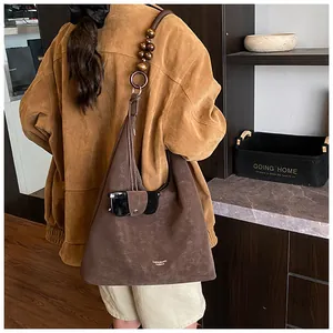 Detail of dark brown faux suede hobo bag with unique wooden bead strap and metal rings