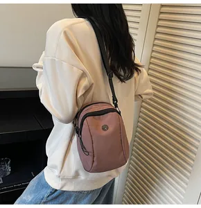 Close-up of pink waterproof oxford fabric crossbody bag showing metal logo and texture