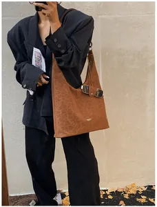 Detail of a brown leopard print suede shoulder bag styled on a person for fall fashion