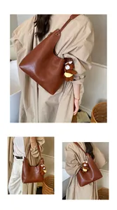 Detail showing a large brown tote bag with a cute plush bear charm for daily commuting