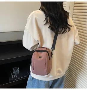 Detail of dusty rose waterproof nylon crossbody bag with adjustable black shoulder strap