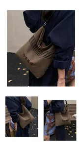 Detailed view of brown canvas bucket bag with black stripes and retro letter printing