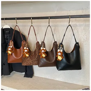 Detail of multi-color tote bags including leopard print and leather with bear charm